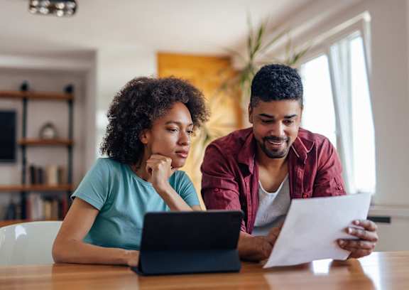 Two people are sitting at a table looking at a document.