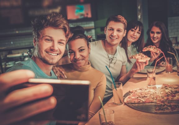 Group of Friends Eating Pizza Taking Photos