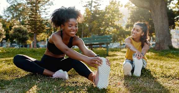 two women sitting on the grass in a park tying their shoes at The Ridge at Chenal Valley, Little Rock, Arkansas