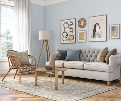 A living room with a white couch, a wooden chair, a wooden table, and a rug.