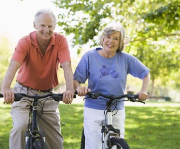 an older couple riding bikes in the park