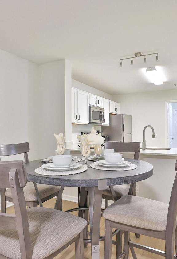 A dining room with a table set for two and a framed picture on the wall.
