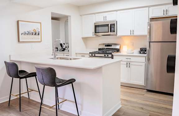 A kitchen with a white countertop and a fridge.