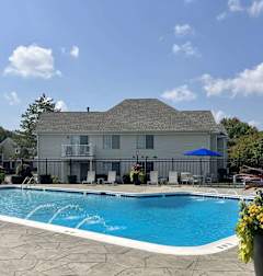 A swimming pool in front of a house with a blue umbrella.