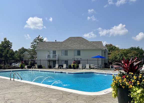 A pool in front of a house with a blue umbrella.