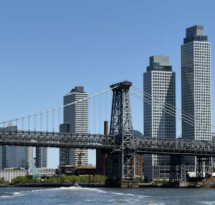 A bridge spans across a body of water with buildings in the background.