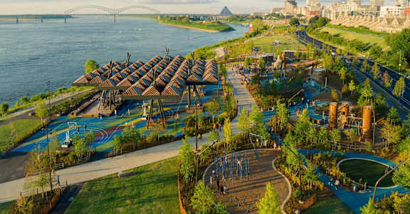 A park with a playground and a bridge in the background.