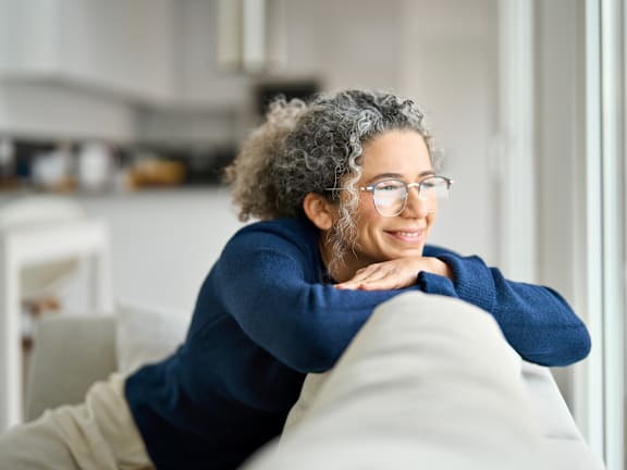 Woman Leaning Over Couch while Looking Out Window