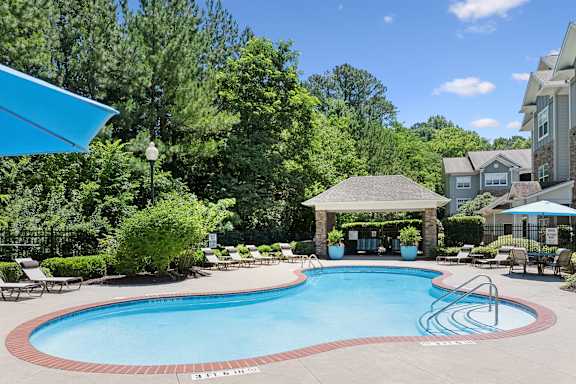 A swimming pool surrounded by trees and a gazebo.