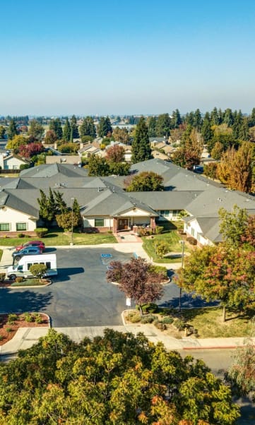 a neighborhood of houses with trees in the foreground and a blue sky in the background at Cogir of Turlock, Turlock, 95382