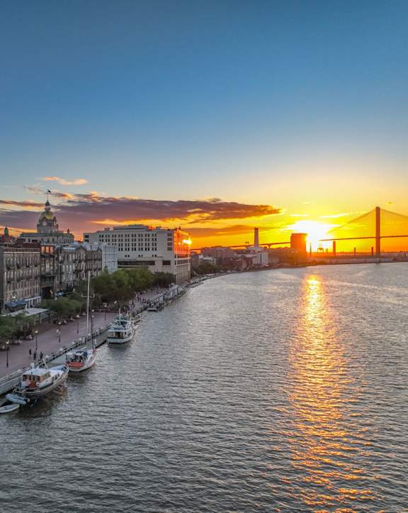 A beautiful sunset over a city with boats docked in the water.