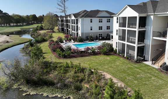 A large white building with a pool in front of it.