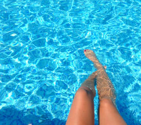 a woman laying in a swimming pool with her legs in the water