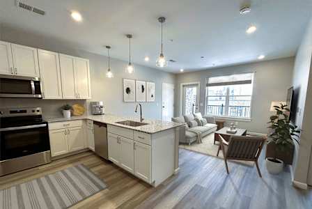 A kitchen with white cabinets and a wooden floor.