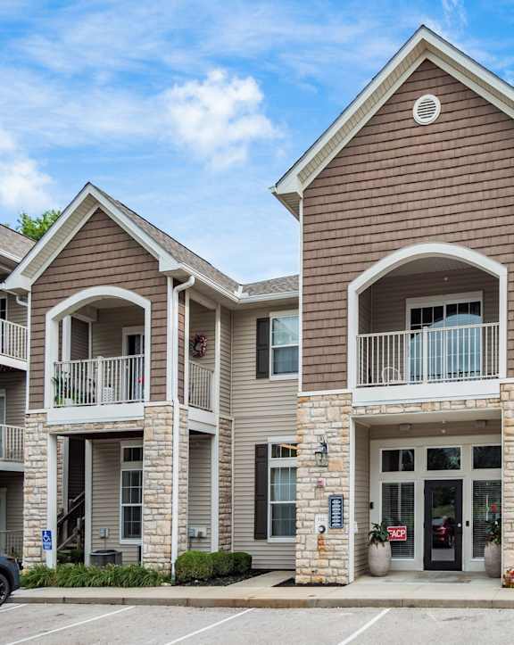 A large two-story apartment building with a stone facade and multiple balconies.