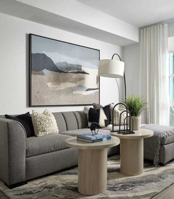 a living room with a gray couch and two round tables