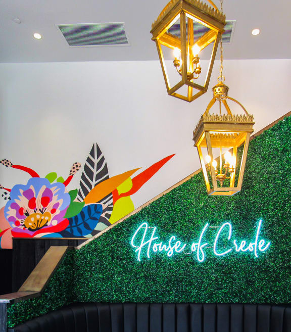 a green astroturf wall with a lit up sign that reads house of creole
