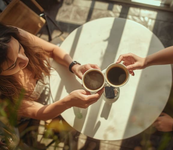 Two people toasting with coffee mugs at a table at Iron Rose, Philadelphia, Pennsylvania