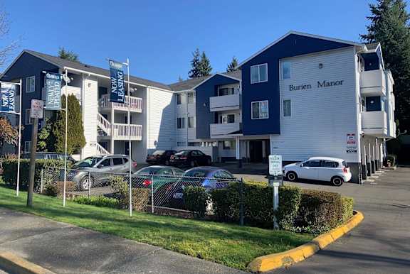 A Burien Manor apartment complex with a parking lot in front.
