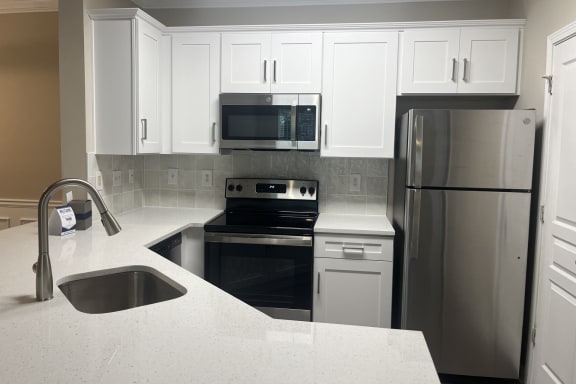 a kitchen with white cabinets and stainless steel appliances at The Berkeley, Duluth, GA