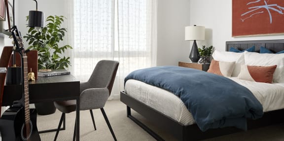 a bedroom with a bed and a desk with a guitar