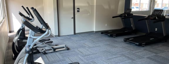 a gym with treadmills and elliptical machines at Courtyard Apartments on Belsly, Moorhead