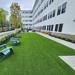 Outdoor courtyard with artificial turf and seating at The Overlook Apartments, Weymouth, 02188