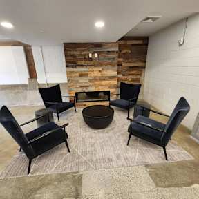 Cozy lounge with fireplace and black armchairs at The Overlook Apartments, Weymouth, MA