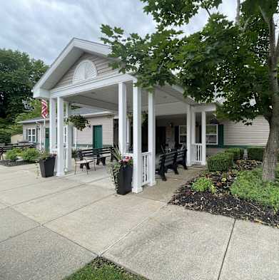 the front of a house with a porch and a tree