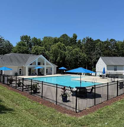 A pool surrounded by a black fence with a house in the background.