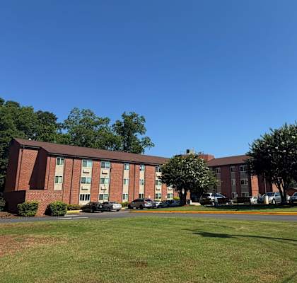 A large red brick building with a parking lot in front.
