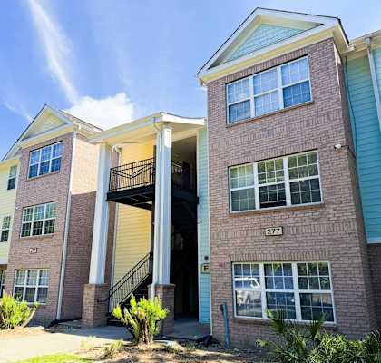 A two-story brick apartment building with a garage door open.
