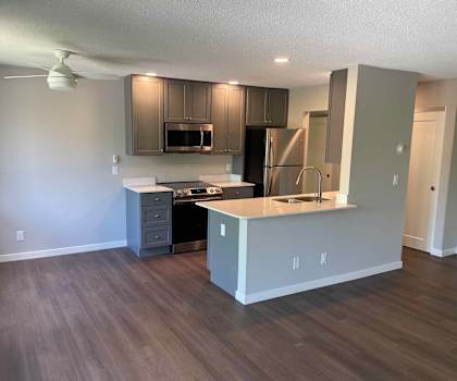 A kitchen with a refrigerator, microwave, and oven.