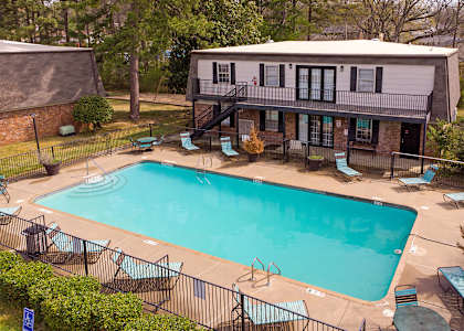 A small pool surrounded by a black fence and chairs.