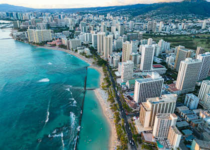 A cityscape with a beach in the foreground and a mountain in the background.