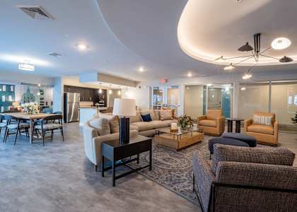 A spacious living room with a variety of seating options and a dining table.