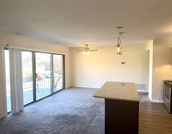 a kitchen and living room with a large glass door to a patio