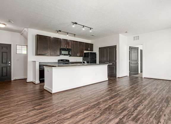 A kitchen with dark wood cabinets and a white island.