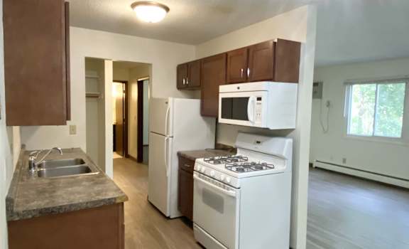 a kitchen with white appliances and brown cabinets