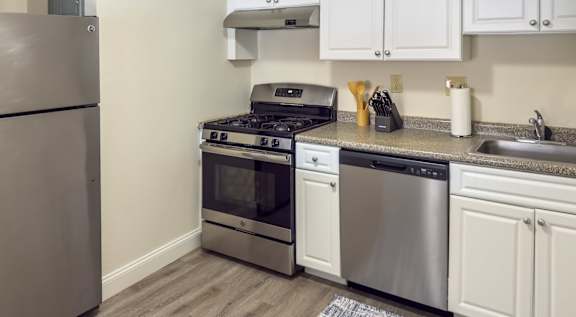 A modern kitchen with a stainless steel refrigerator and a wooden stool.