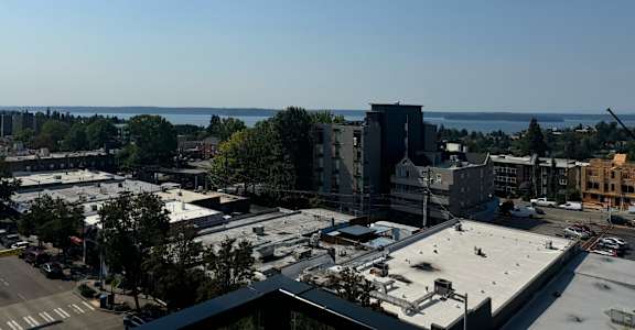 an aerial view of a city with a body of water in the background at Junction Central, Washington, 98116