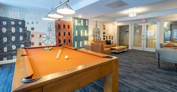 A pool table is in the middle of a room with a blue carpet.