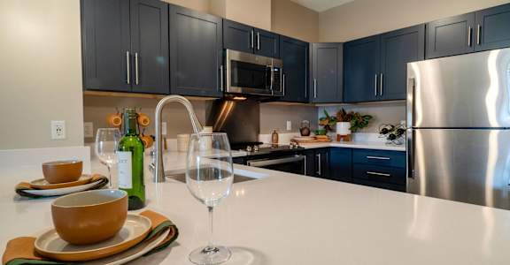 A kitchen with a white counter top and a stainless steel refrigerator.