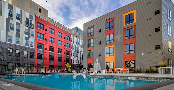 A swimming pool is in front of a building with red and orange doors at Center Square Lofts West, Allentown, PA