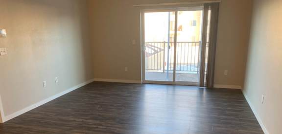 an empty living room with a sliding glass door leading to a balcony