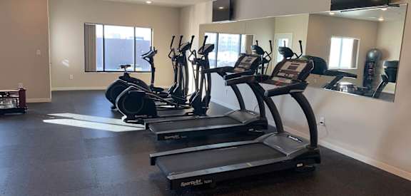 a row of treadmills in a gym with a large mirror on the wall