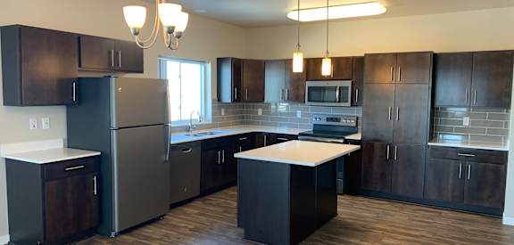 an empty kitchen with dark wood cabinets and stainless steel appliances