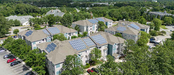 A bird's eye view of a residential area with houses and solar panels on the roofs.