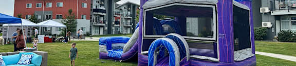 A purple castle-like inflatable structure is in the foreground of a grassy area.