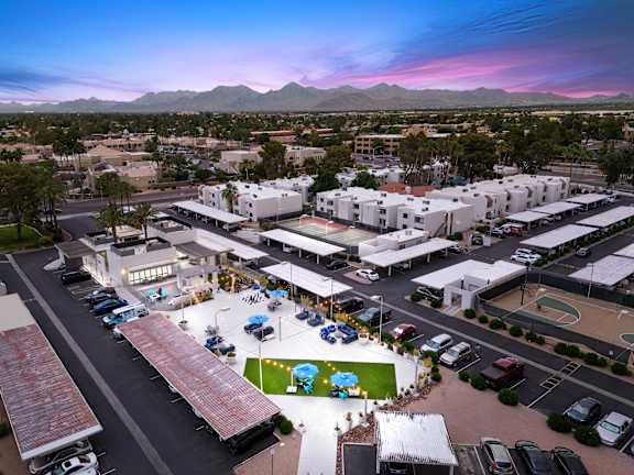an aerial view of a shopping center at sunset with mountains in the background